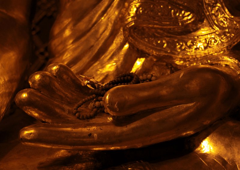 golden buddha hand with prayer beads resting on palm, divine trust by amyra mah